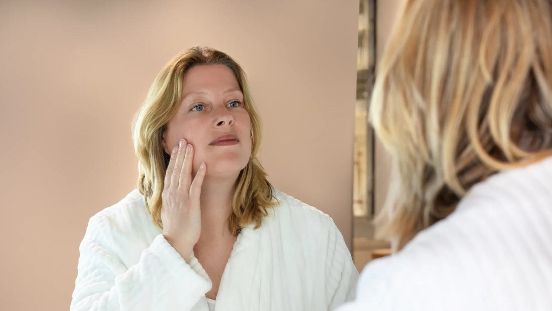 Vrouw bekijkt haar huid in de spiegel na het aanbrengen van retinol