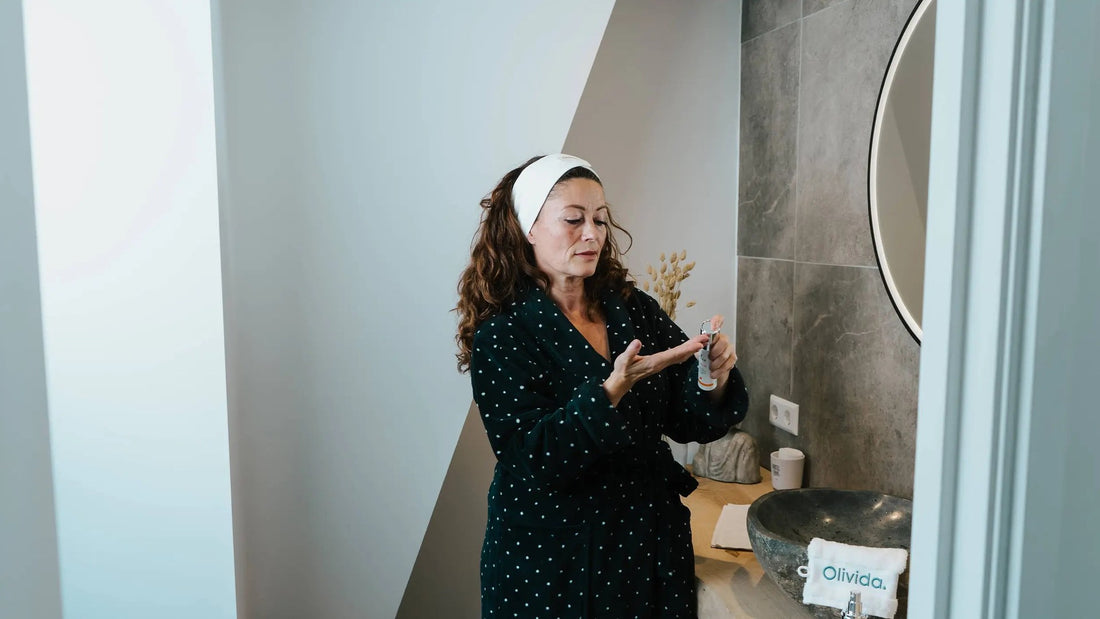 Vrouw in badjas doseert een serum voor de spiegel in de badkamer