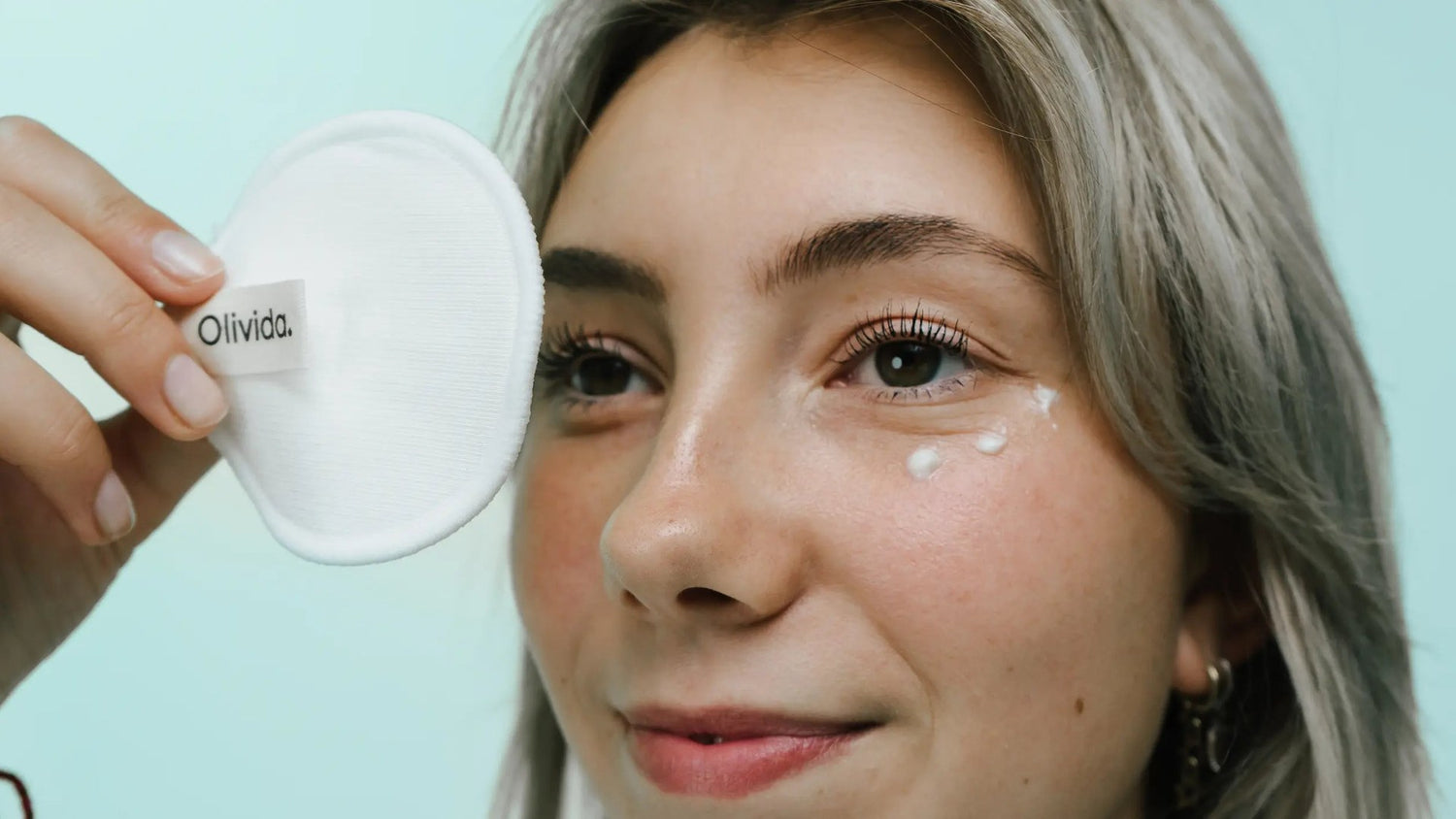 Vrouw met een Olivida-wattenschijfje en dotjes crème op haar wang