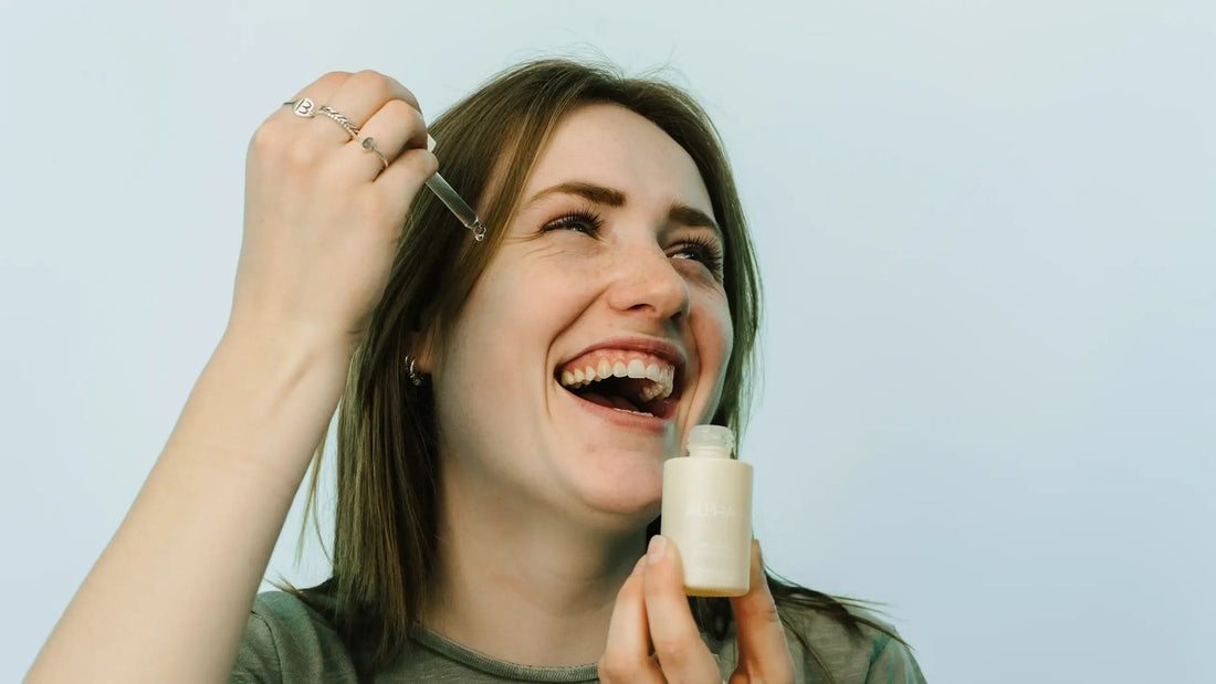 Lachende vrouw met een serum in haar hand, met lachlijntjes rond haar ogen