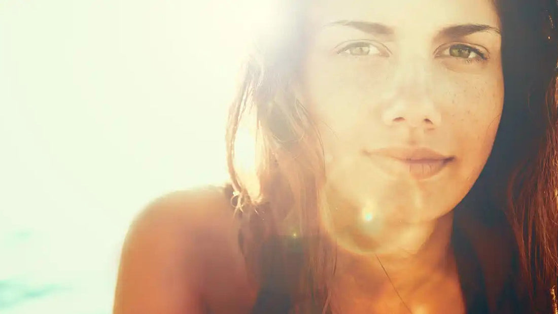Vrouw met sproeten in de felle zon op het strand; een verbrande huid begint met te veel zon