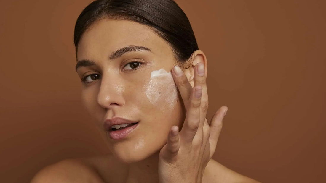 Vrouw smeert een dagcrème met SPF uit over haar wang