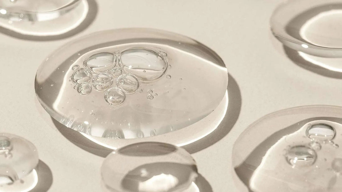 Heldere druppels hydraterende gel op een zandkleurige ondergrond