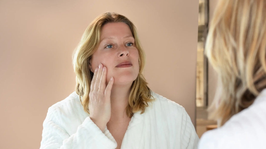 Vrouw voelt aan de huid van haar wang in de spiegel
